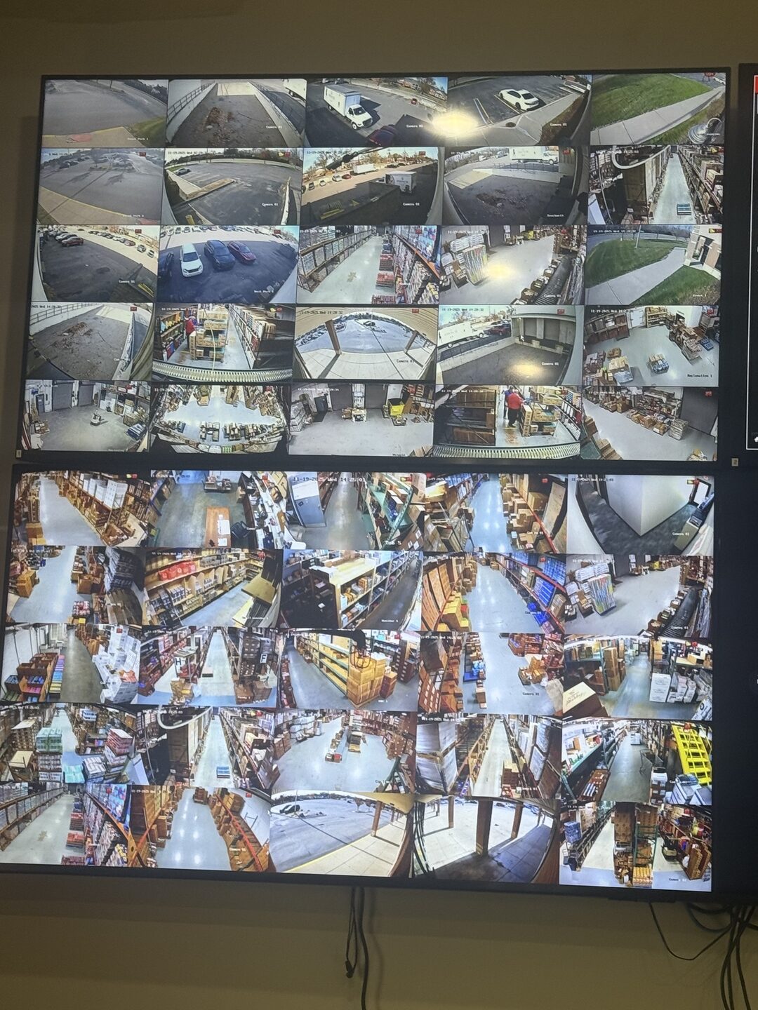 Dual monitors displaying a dense grid of warehouse security camera feeds